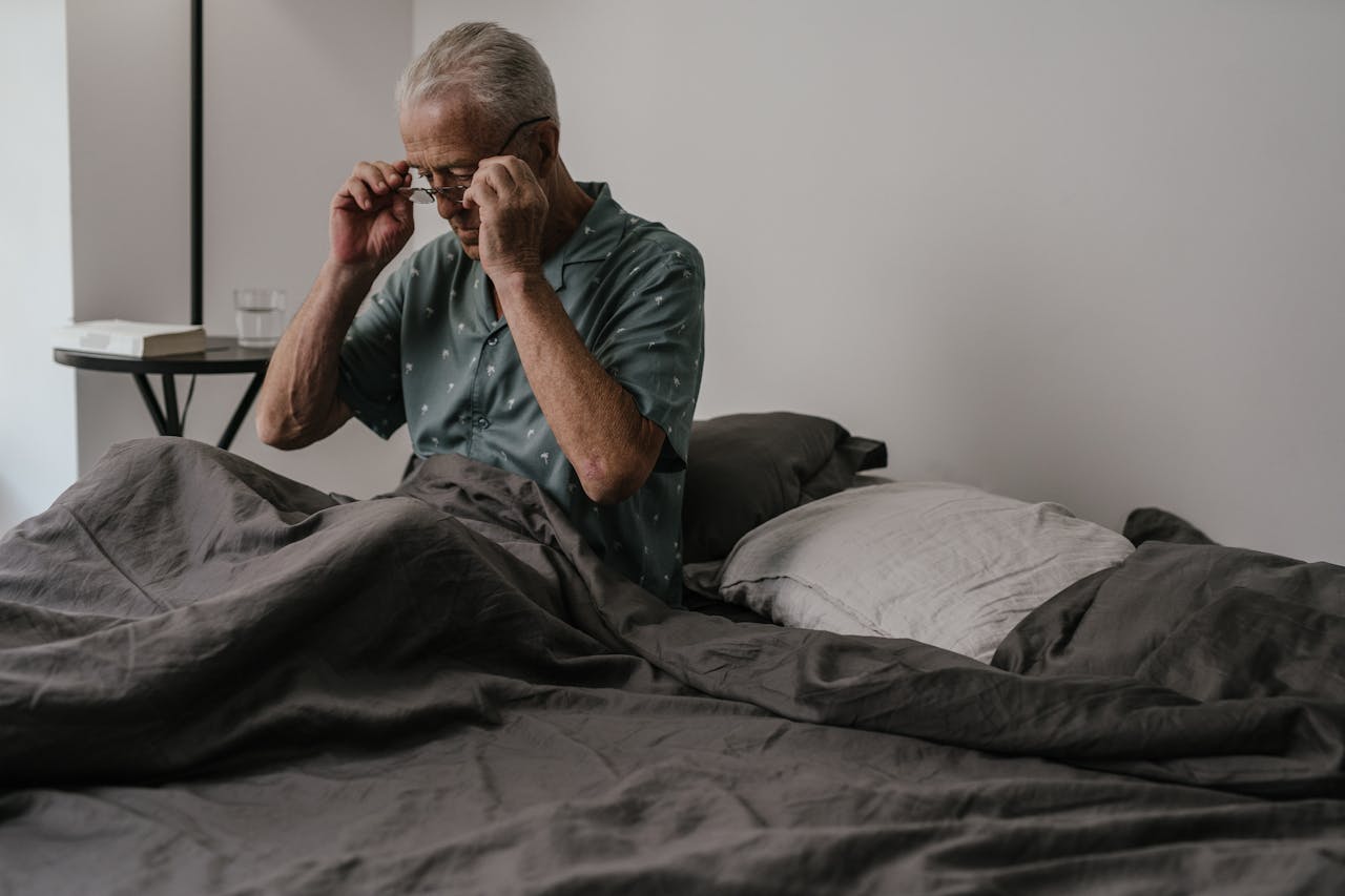 Een oudere man in zijn nachtmode gezeten in bed